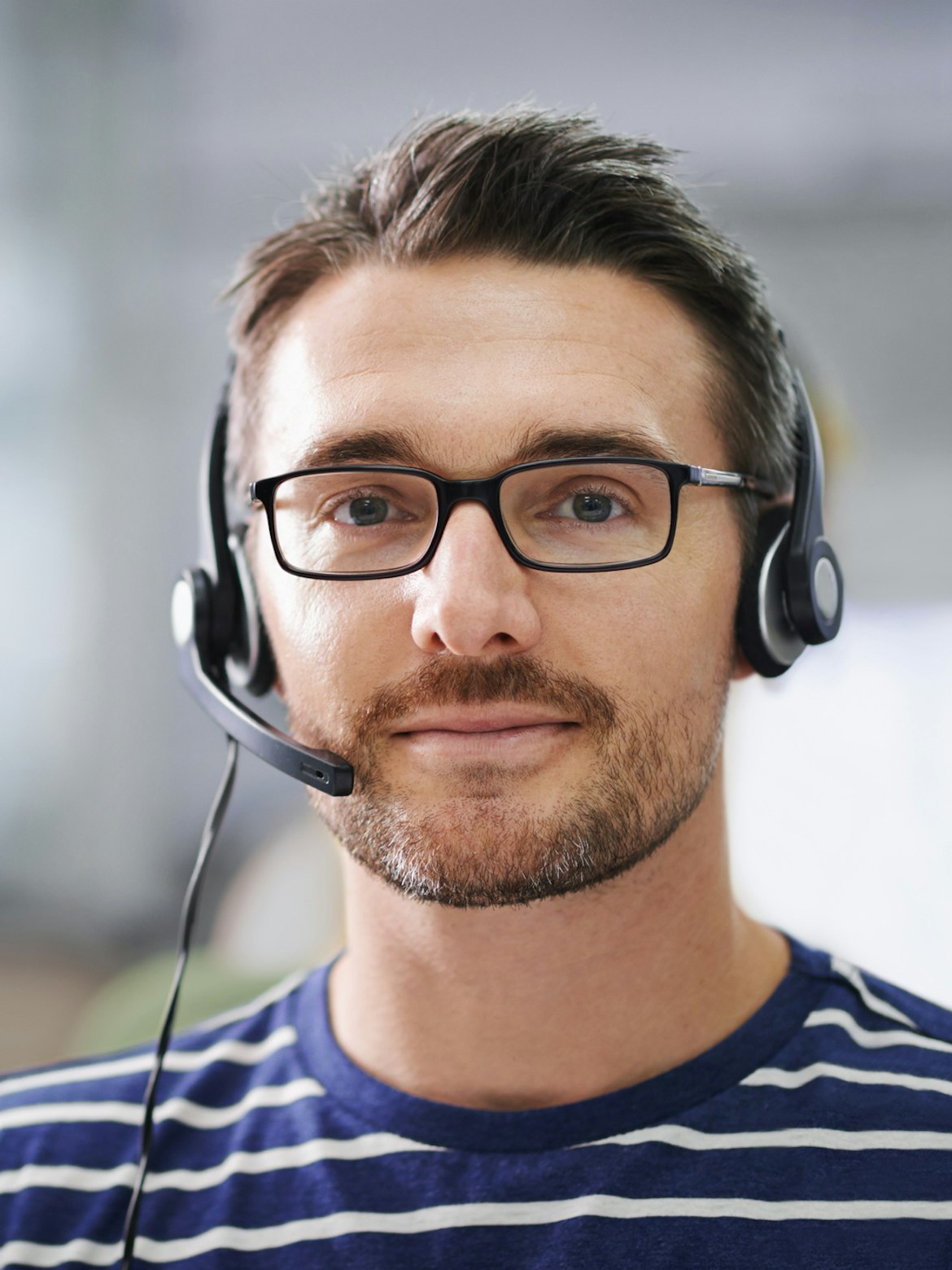 Mann i kundeservice med hodetelefoner ser i kamera