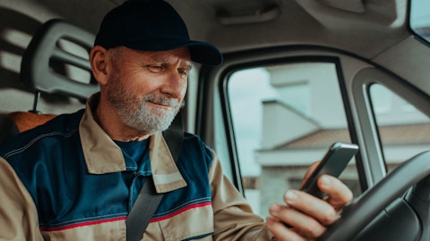 En mann sitter i en bil og ser på telefonen sin.
