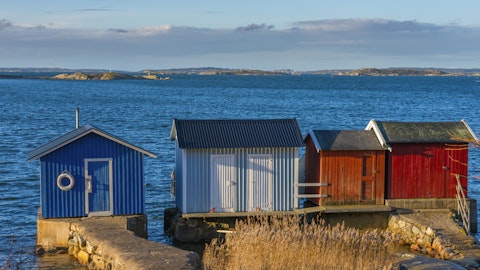 Et rødt lite hus i strandsonen.
