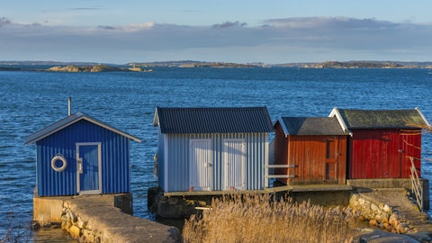 Et rødt lite hus i strandsonen.