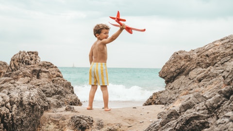 Et barn som leker med et lekefly på stranden.