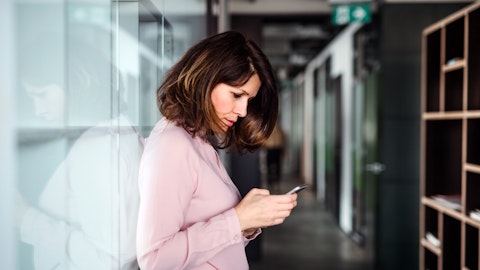 En kvinne stirrer på mobilen og ser bekymret ut.