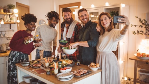 En gruppe mennesker står rundt et bord med mat og tar et selfie. Foto