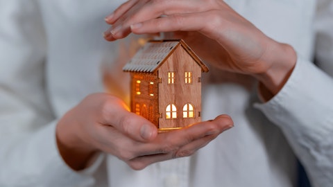 En person holder et miniatyr hus i hånden