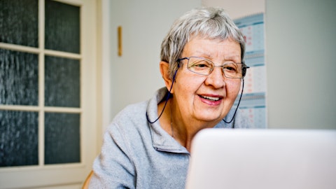 En eldre kvinne sitter foran datamaskinen.