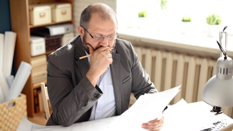 En entreprenør sitter og leser gjennom papirer mens han tenker hardt.