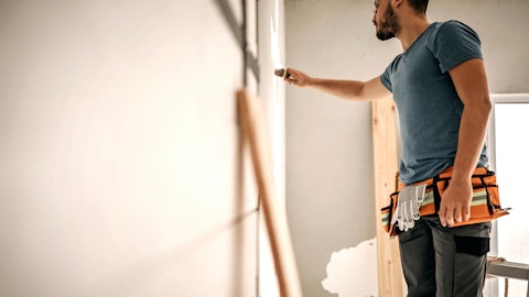 En entreprenør står og maler veggen i en leilighet.