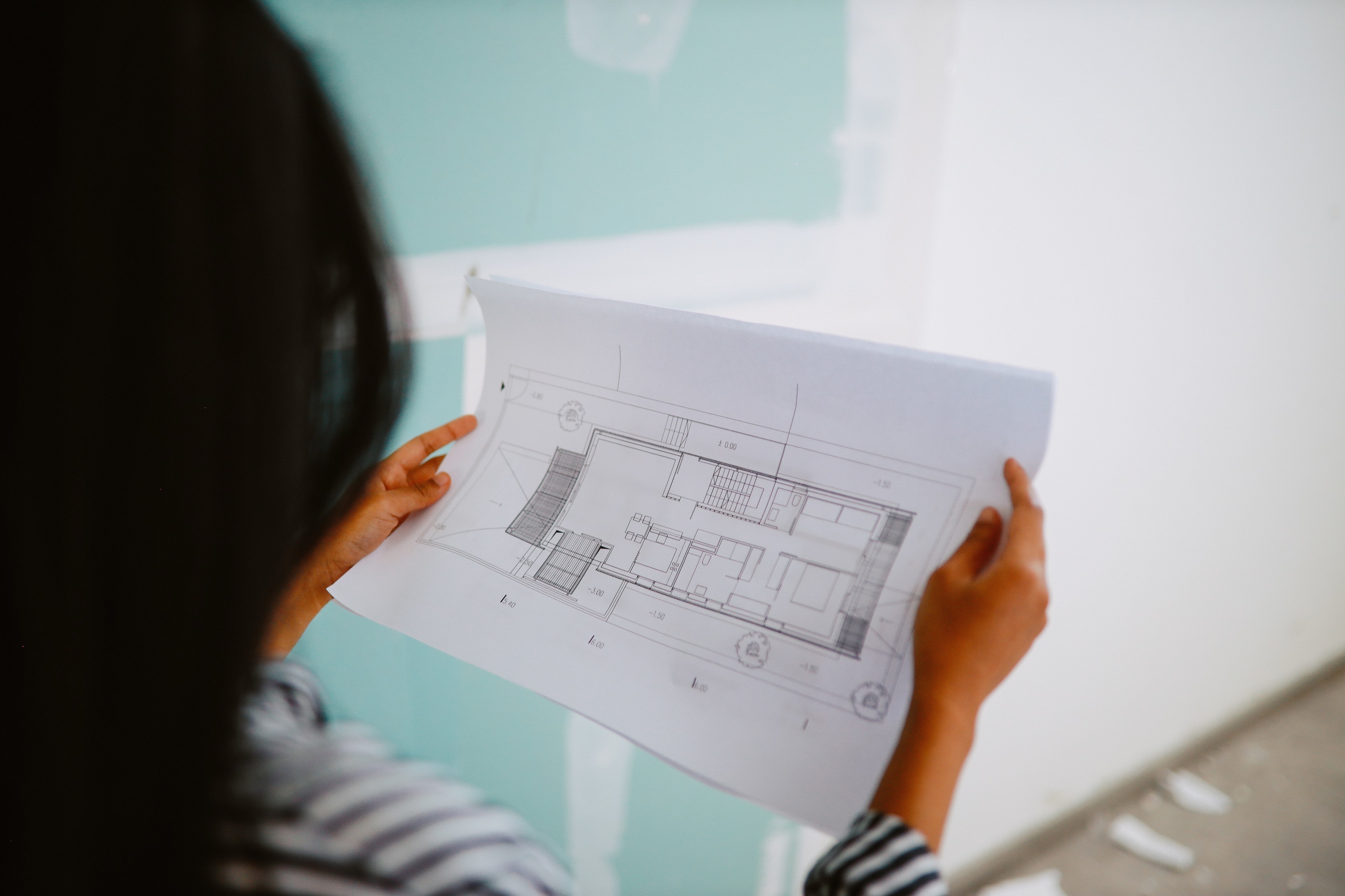 En mørk-håret kvinne kikker på en byggeplan