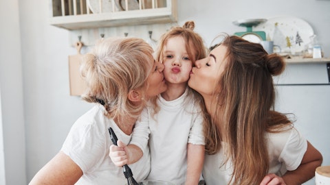 A little girl gets kissed on each cheek by her mother and grandmother.