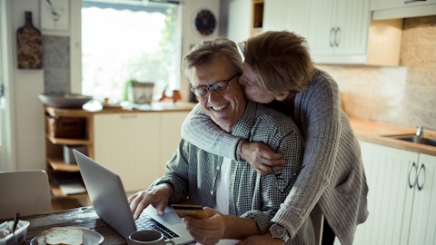En kvinne holder rundt mannen sin mens han sitter på laptopen.