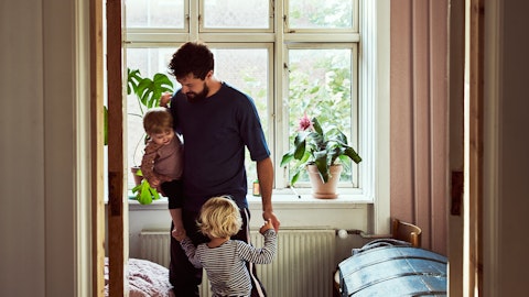 En far står foran et vindu med sine to små barn.
