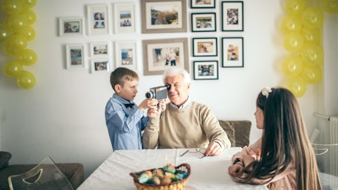 En gutt hjelper bestefaren sin med et filmkamera. Foto