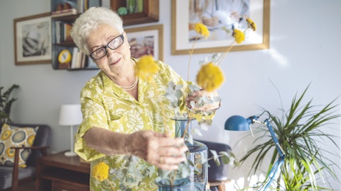 En eldre dame fikser blomster i en vase.