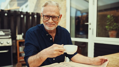 Smilende mann som drikker kaffe og leser avisen