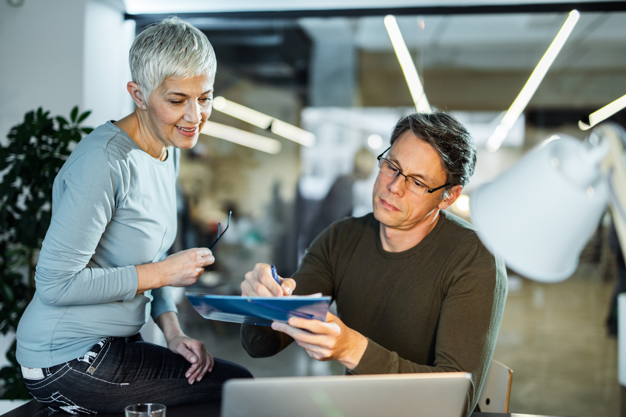 Dame og mann snakker over dokumenter.