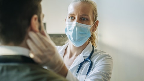 en kvinnelig lege med munnbind undersøker en pasient.