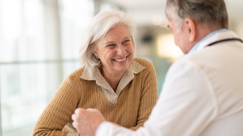 Eldre kvinne smiler i samtale med legen.