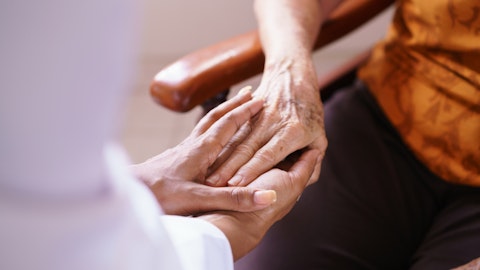 En sykepleier holder hånden til en eldre dame.