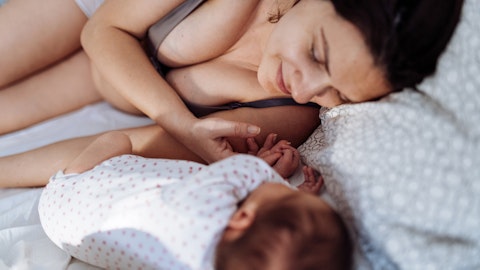 Mor med nyfødt barn ligger i sengen og nyter øyeblikket