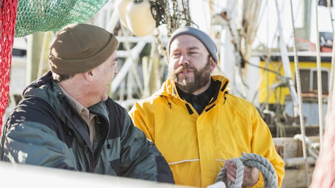 To yrkesfiskere snakker med hverandre mens de jobber.