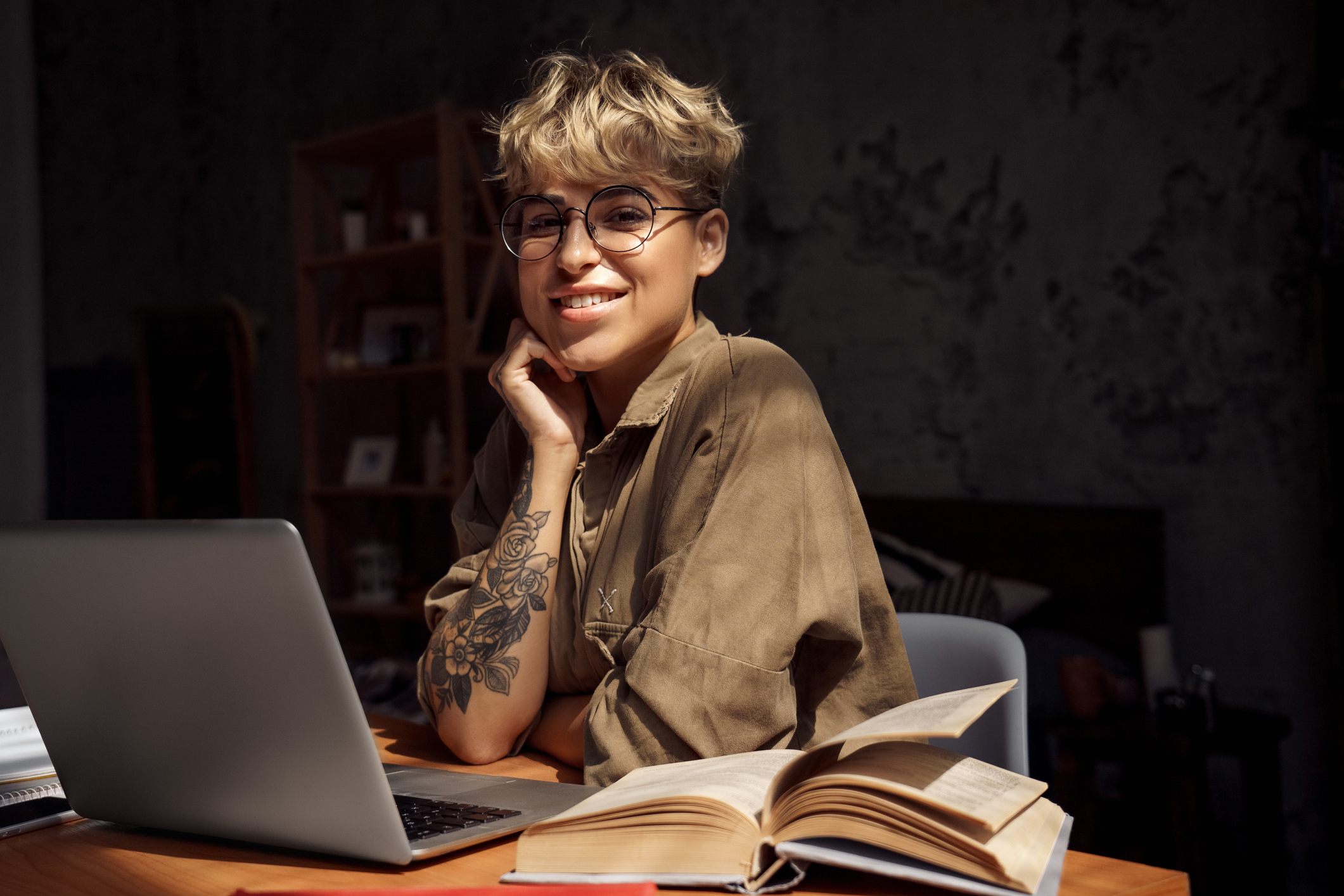 En kvinne med tatoveringer sitter foran laptopen.