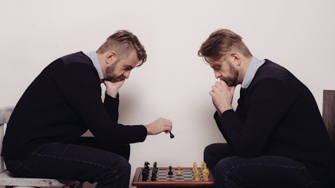 To menn som ser veldig like ut sitter og spiller sjakk.