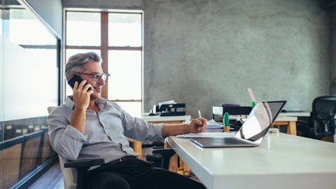 Mann i skjorte som snakker i telefonen foran sin laptop.