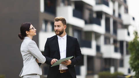 En mann og en dame står og prater utenfor et leilighetskompleks