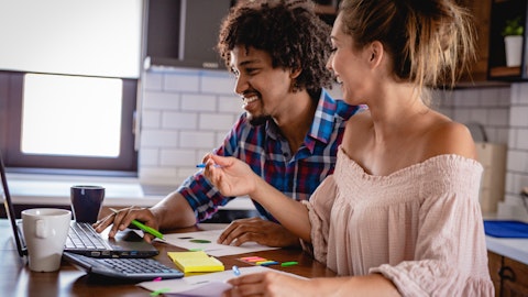 En mann og en dame sitter med regnskap forran en PC. Foto