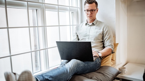 En mann sitter i en vinduskarm med en laptop