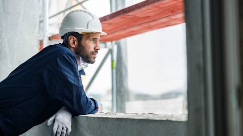 En mann med hjelm står på en byggeplass og ser utover