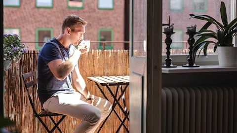 En mann sitter på terrassen og drikker kaffe.