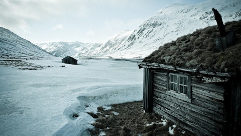 Gårdsbruk på fjellet dekket av snø.