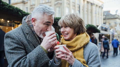 En mann og en kvinne drikker varm sjokolade på julemarkedet.