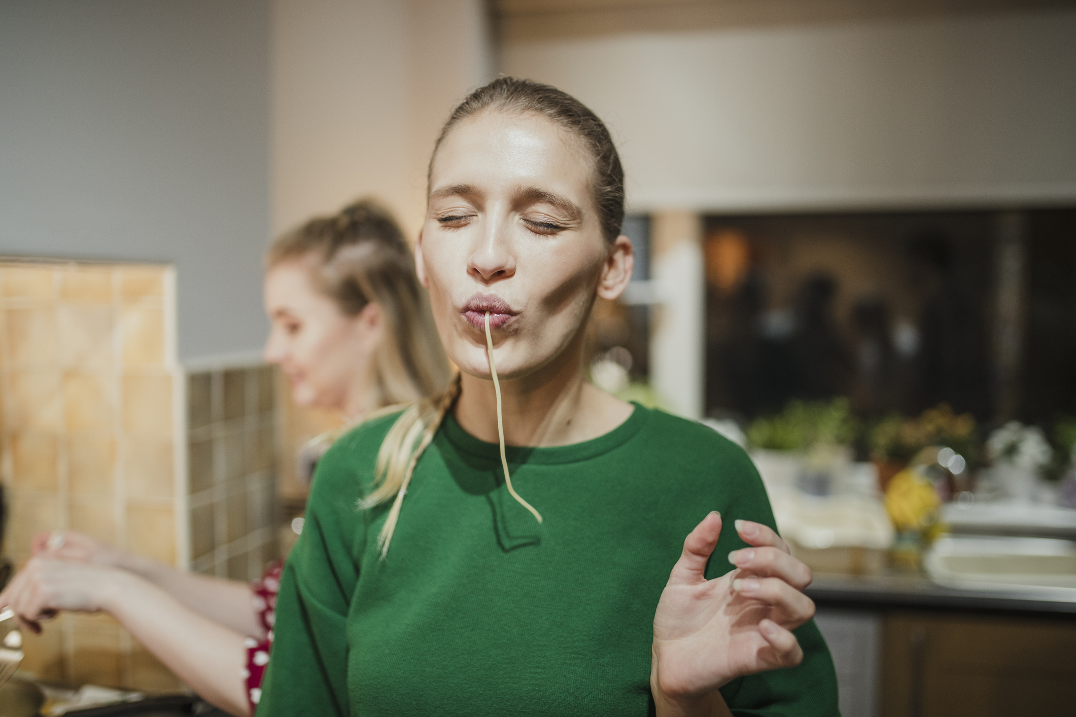 En kvinne som spiser spaghetti på kjøkkenet.