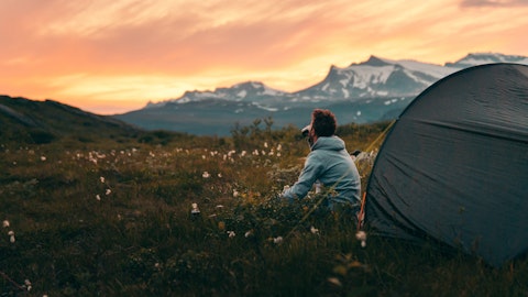 mann sitter foran telt, solnedgang
