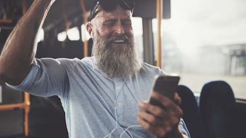 En mann som ser på sin telefon og smiler på en buss.