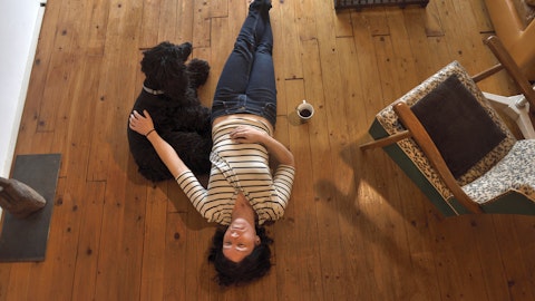 En kvinne ligger på gulvet sammen med hunden sin.