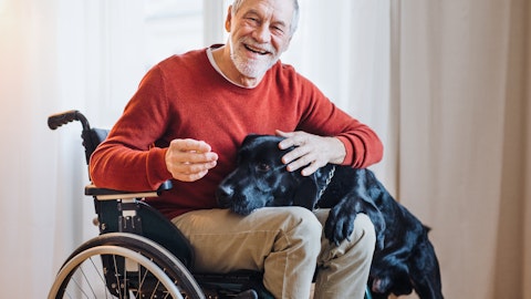 Glad mann i rullestol med en hund på fanget.